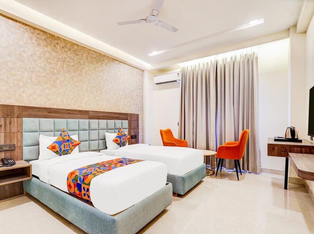 Twin bed room with AC and seating area at Amrit Residency